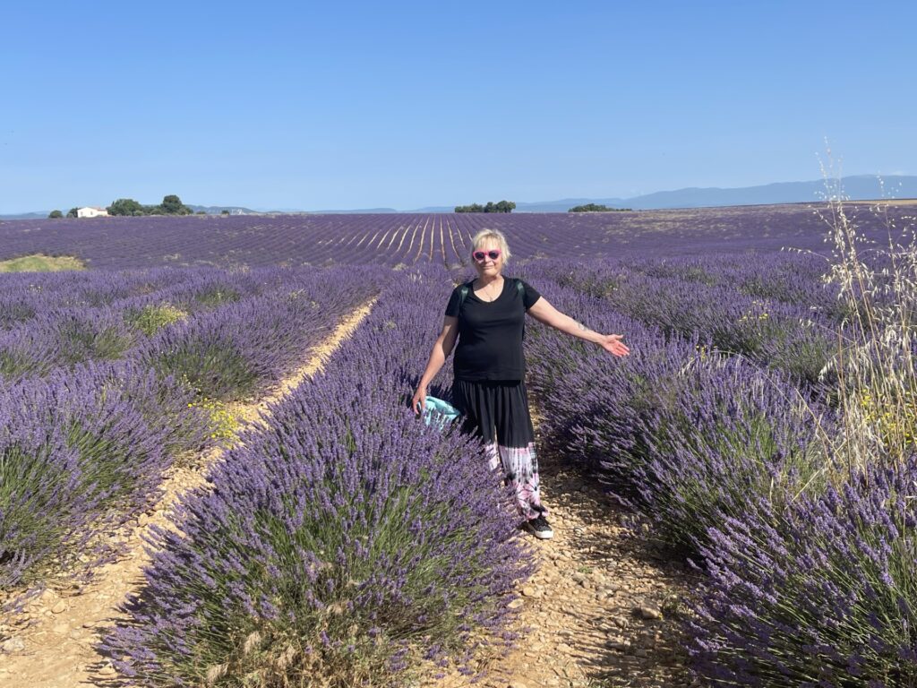 Woman stands in the middle of a purple field. 